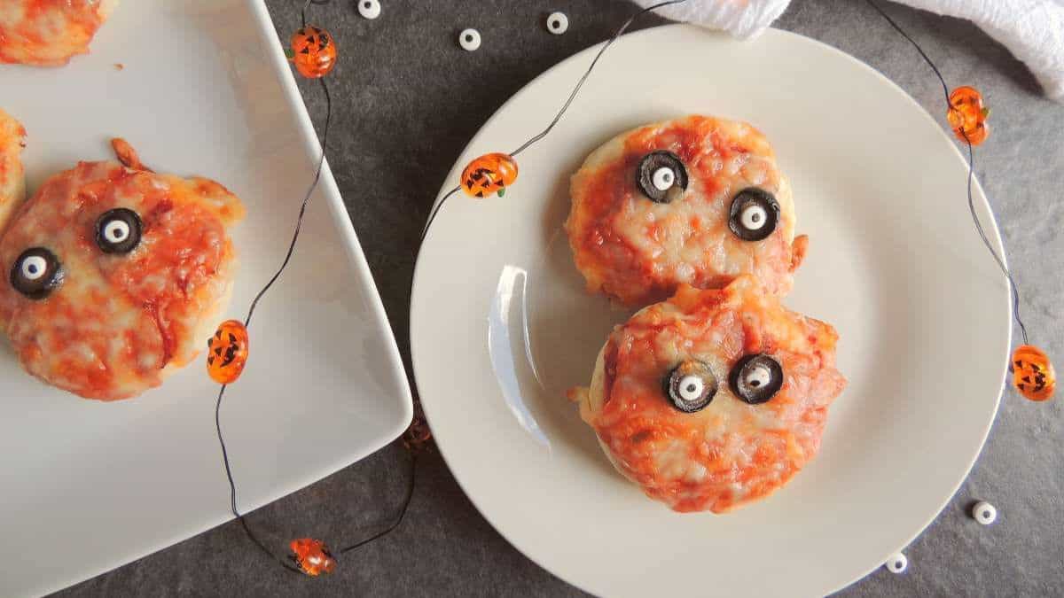 mini round pizzas with black olives for eyes
