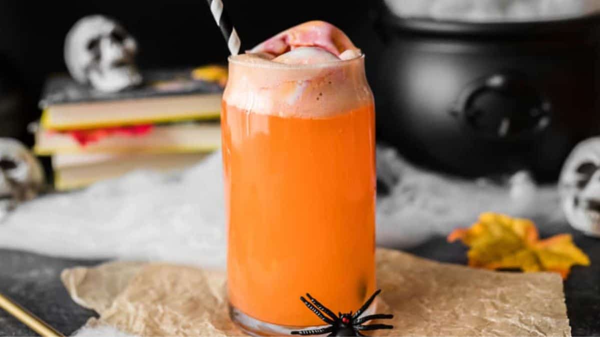 orange cocktail in a tall glass with striped straw