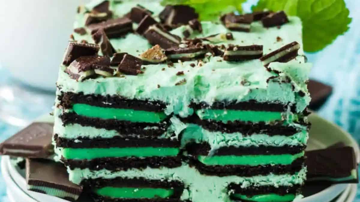 a slice of a layered cake with chocolate mint cookies, mint candy and tinted whipped cream