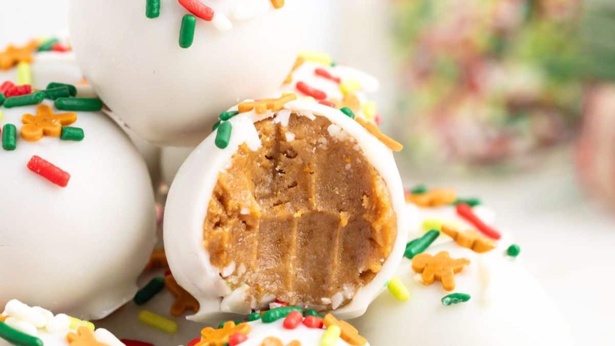 a pile of white chocolate covered gingerbread truffles with one with a bite