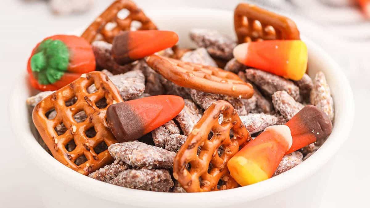 a bowl with muddy buddies, pretzel squares, and candy corn