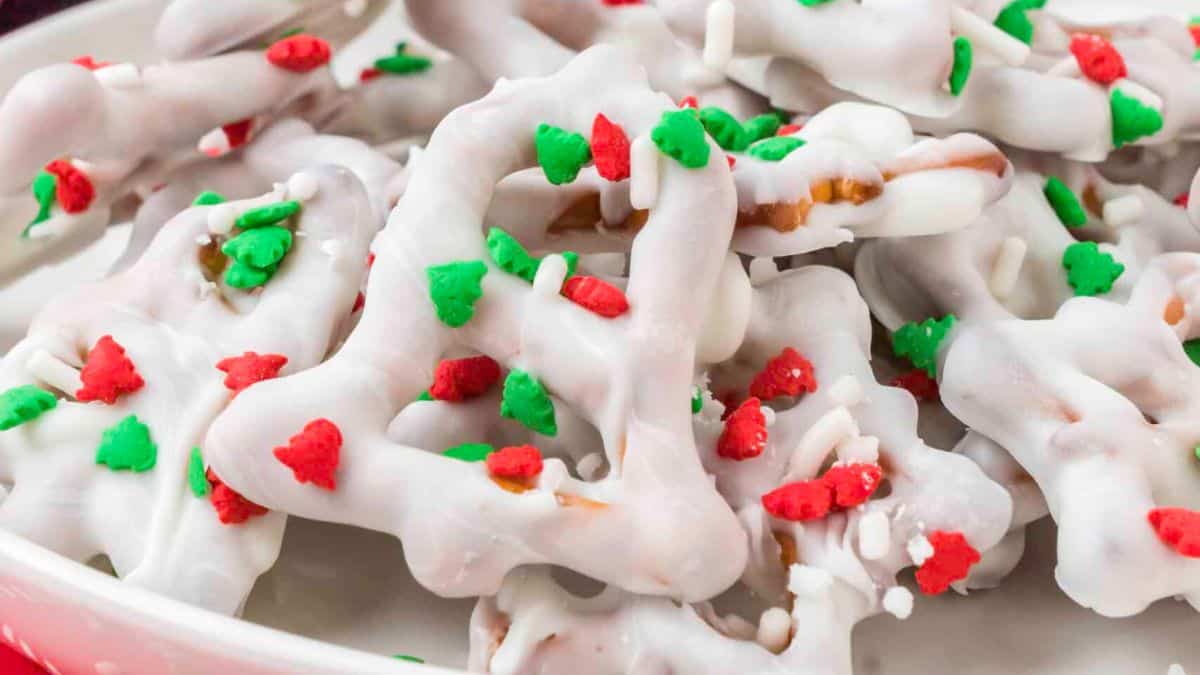 bell shaped pretzels covered in white chocolate and christmas tree shaped red and green sprinkles