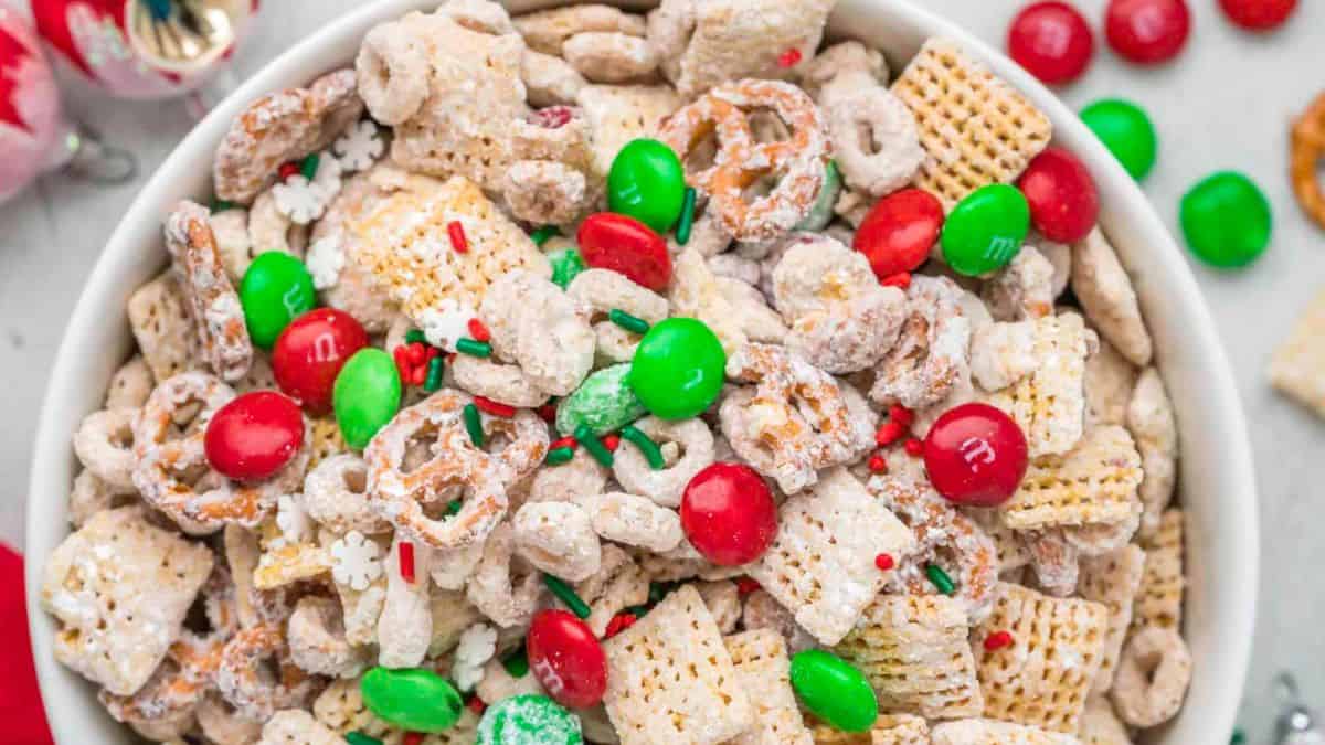 a bowl with sweet chex mix with white chocolate, pretzels, red and green M&M candy