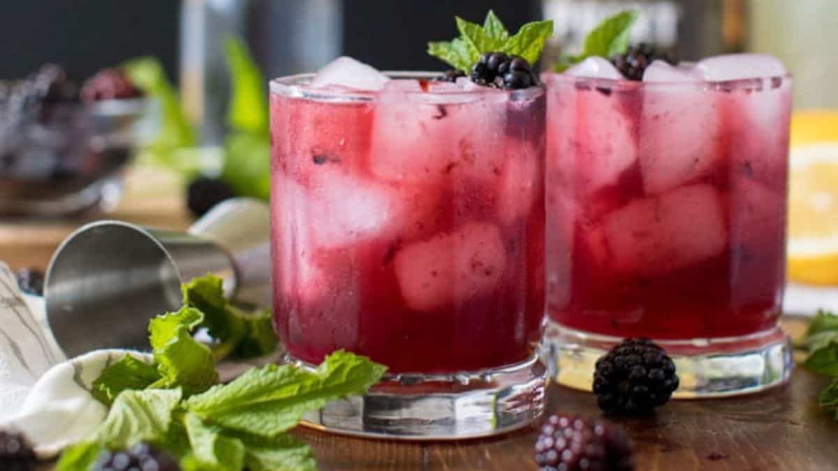 Glasses of blackberry bourbon lemonade with fresh blackberry on top.