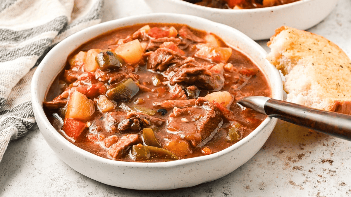 A plate of slow-cooked Hungarian goulash with bread on the side.