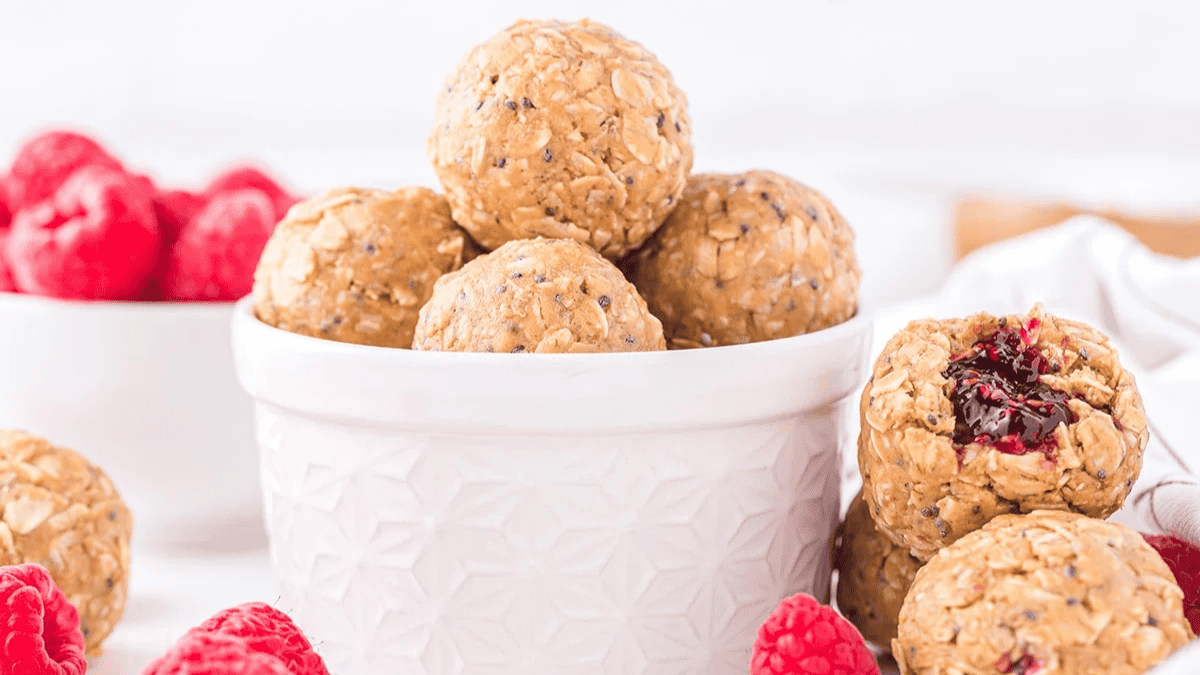Peanut Butter & Jelly Energy Balls in a dessert bowl with raspberries.
