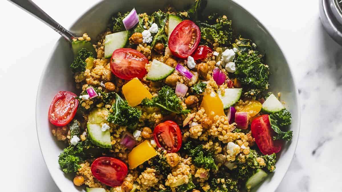 A bowl of colorful chili lime quinoa salad with kale and roasted chickpeas.