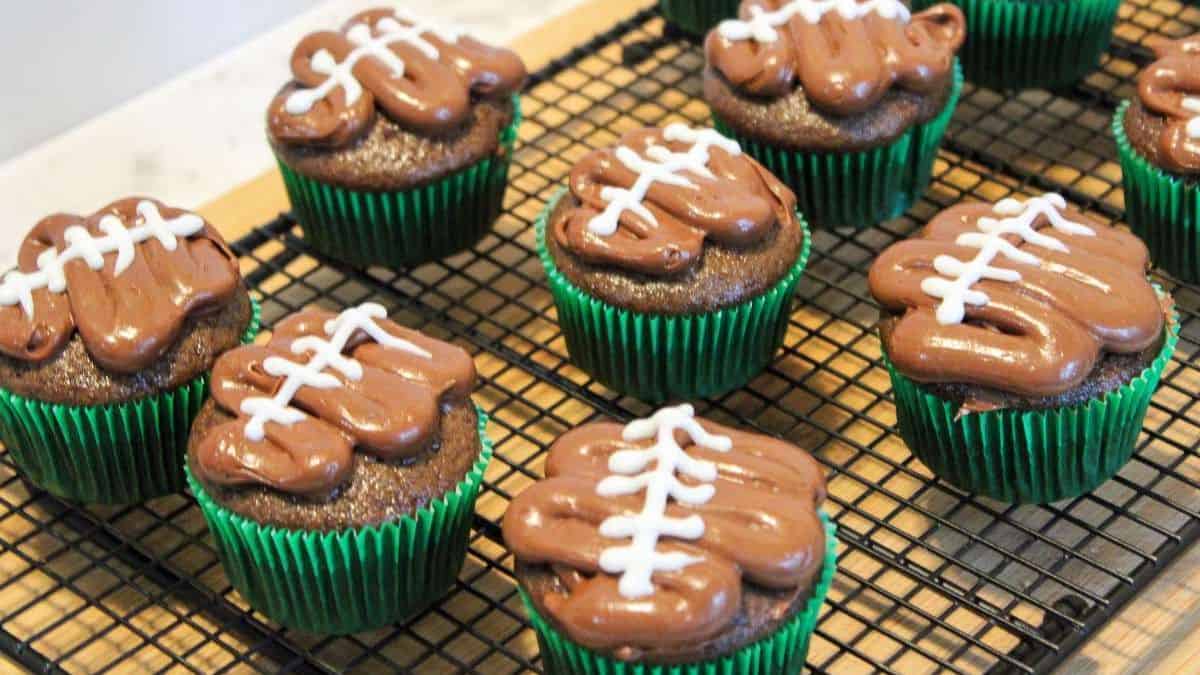 Football cupcakes in a cooling rack.