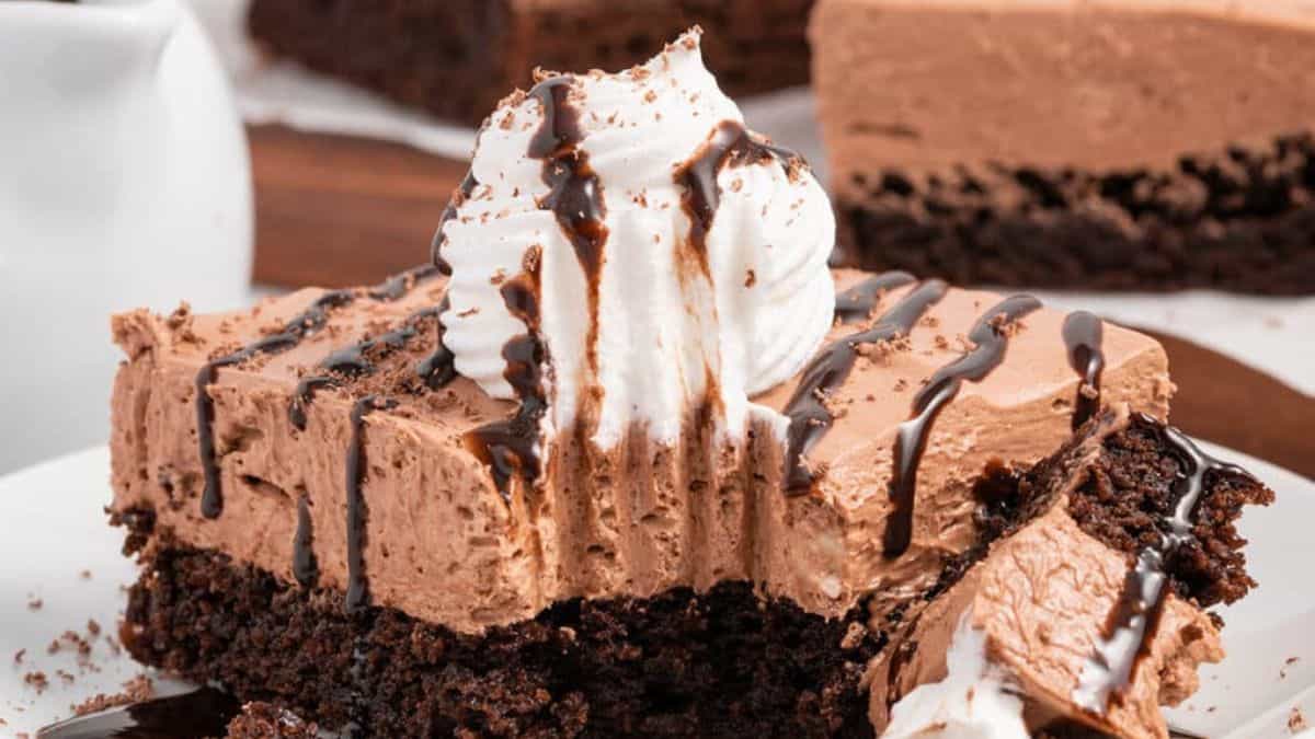 Perfect sliced and bite of French silk brownies topped with whipped cream drizzled with chocolate syrup.