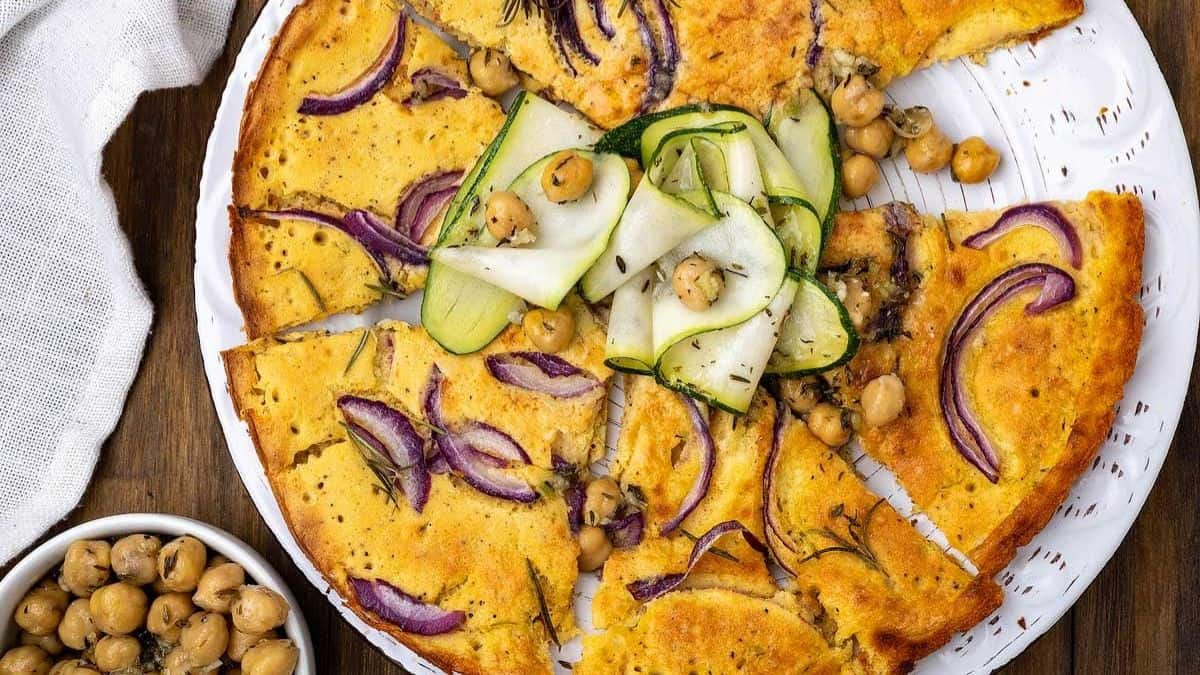 Whole serving of farinata - Italian chickpea pancake flatbread with chickpea on the top.