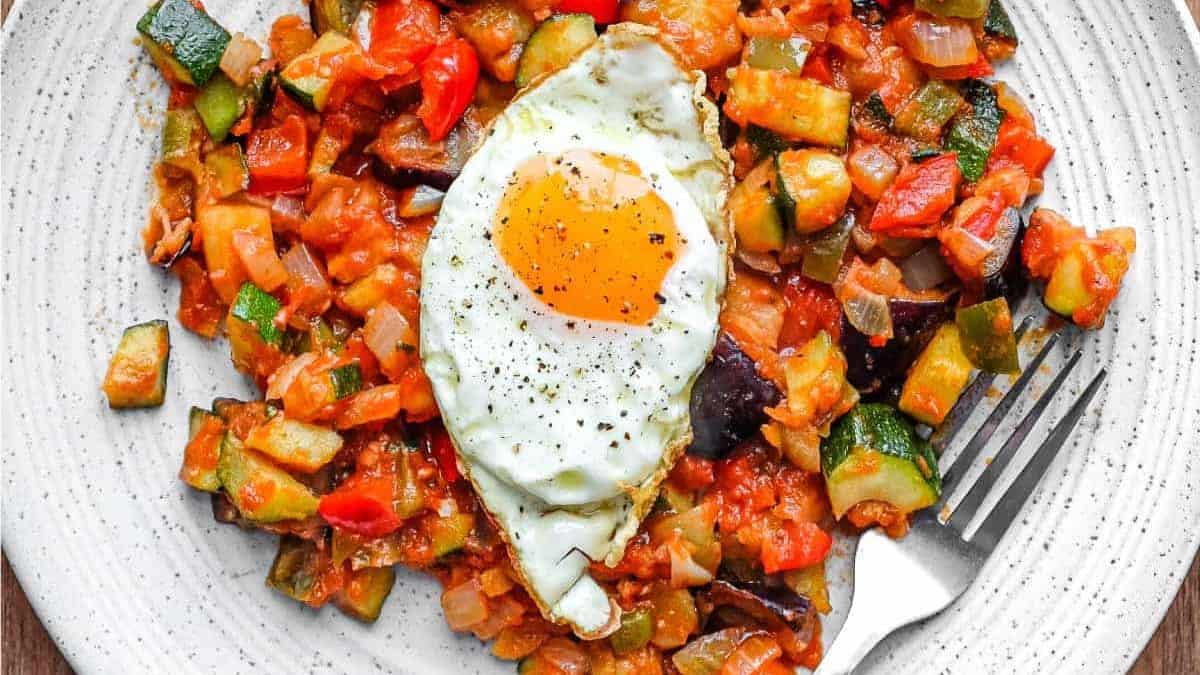 Beautifully plated pisto manchego crowned with fried egg with crispy edges.