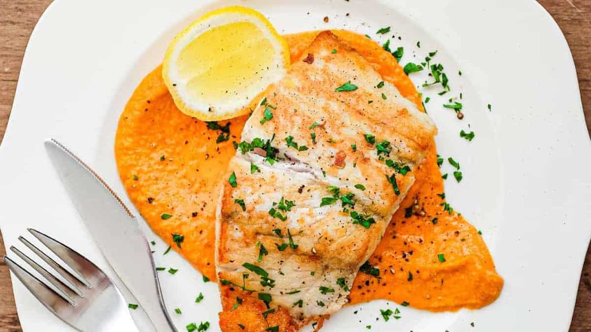 Gorgeously plated fish with romesco sauce and a sliced of lemon