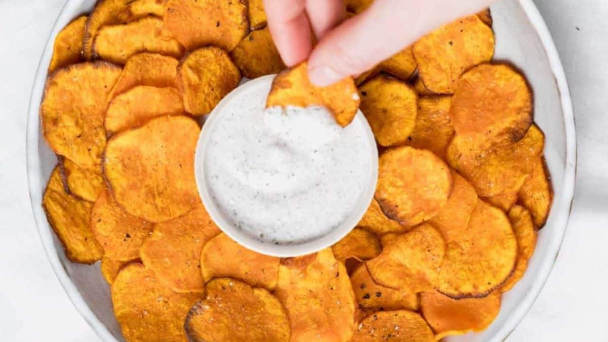 Plate full of air-fried sweet potato chips with dip in the center.