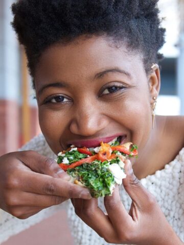 Woman eating a slice of healthy pizza