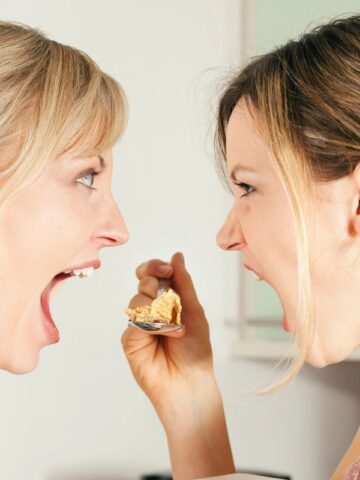 two women yelling over a spoon with food on it.