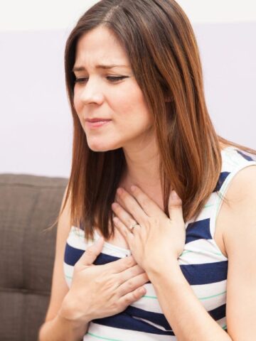 woman holding her chest with heartburn