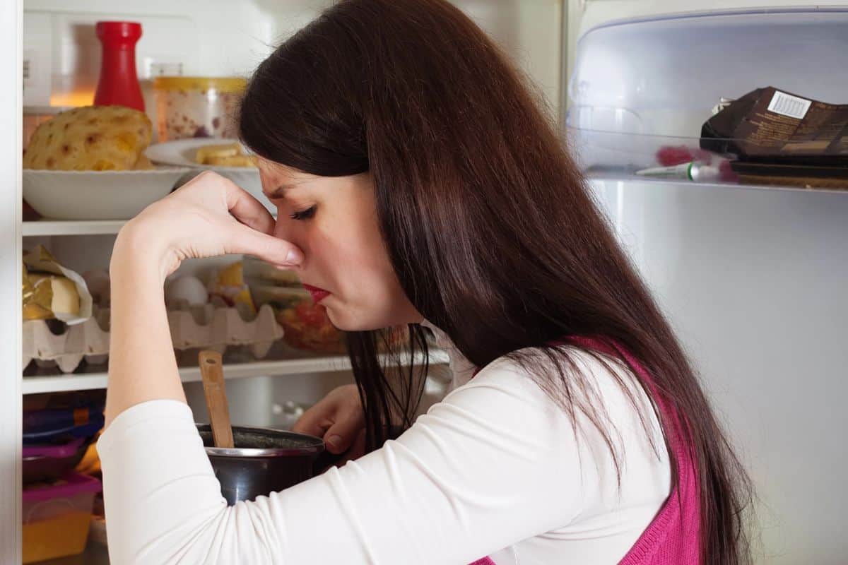 woman smelling bad food from the fridge