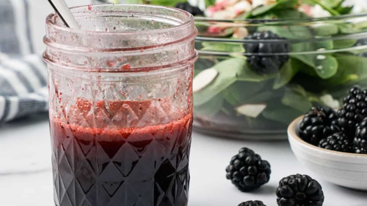 Blackberry balsamic vinaigrette dressing with blackberries and green salad on the background.