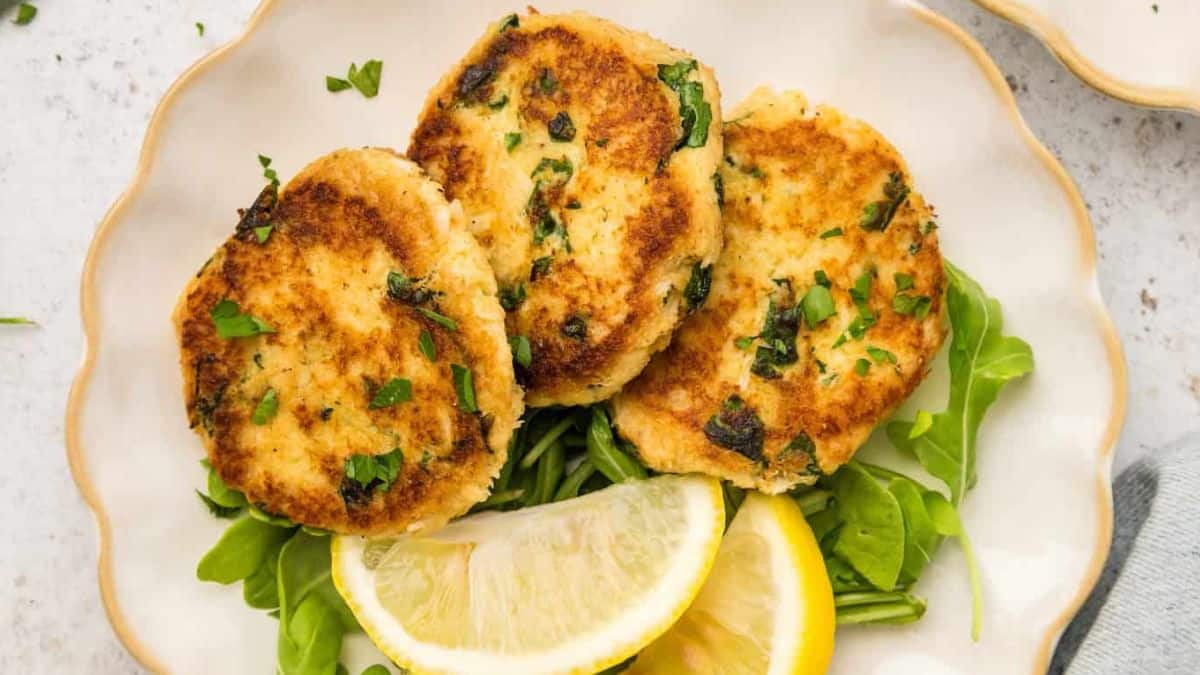 Beautifully plated crab cakes with lemons on the side.