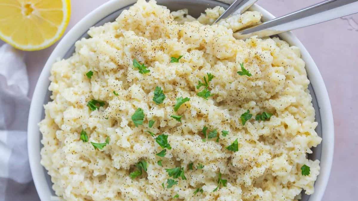Freshly cooked creamy parmesan rice garnish with fresh chopped parsley and sliced lemon on the side.
