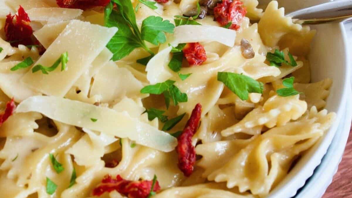 A bowl of creamy bow tie pasta garnished with chopped fresh parsley