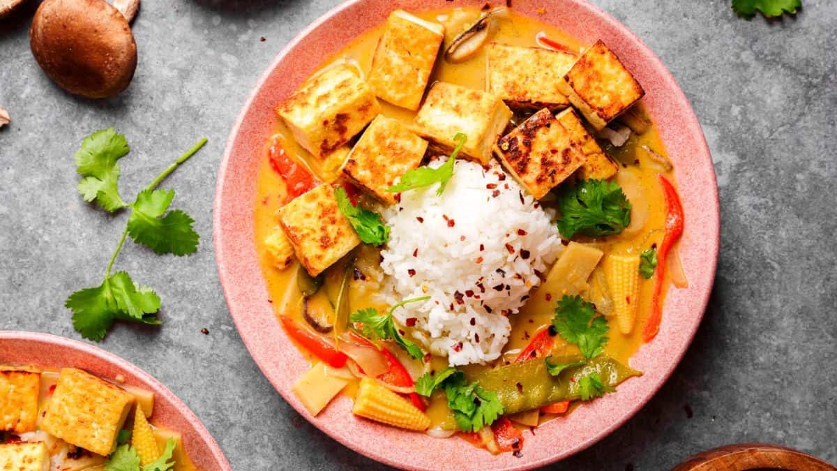 A plate of vegan Thai green curry with crispy tofu.