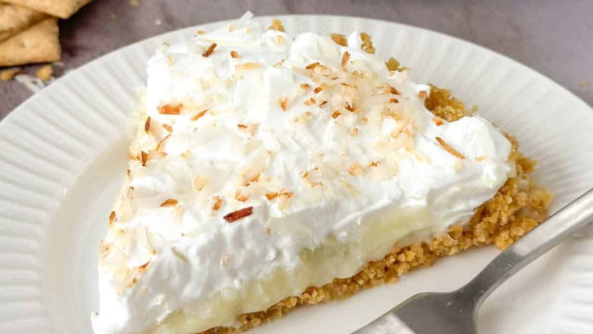 A slice of old fashioned coconut cream pie with crust made of graham cracker.