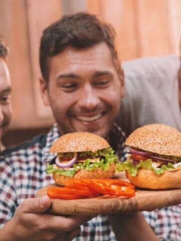 Three men holding burgers.