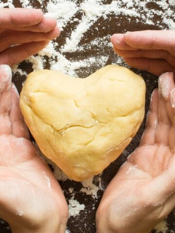 adult and kids hand wrapped around a heart of dough