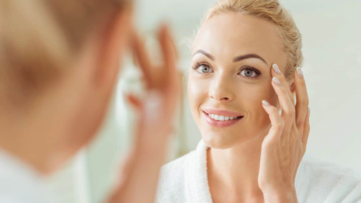 happy woman looking at skin in mirror