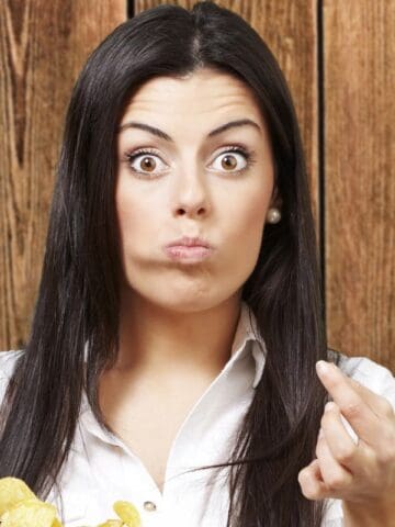 woman holding chips looking surprised