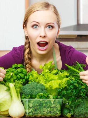 woman with thumbs up over lots of green vegetables