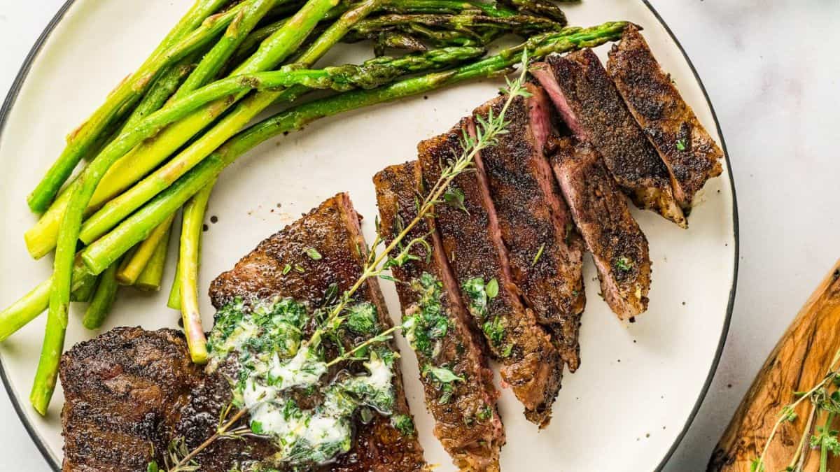 Pan-grilled steak with asparagus on the side served in a plate.