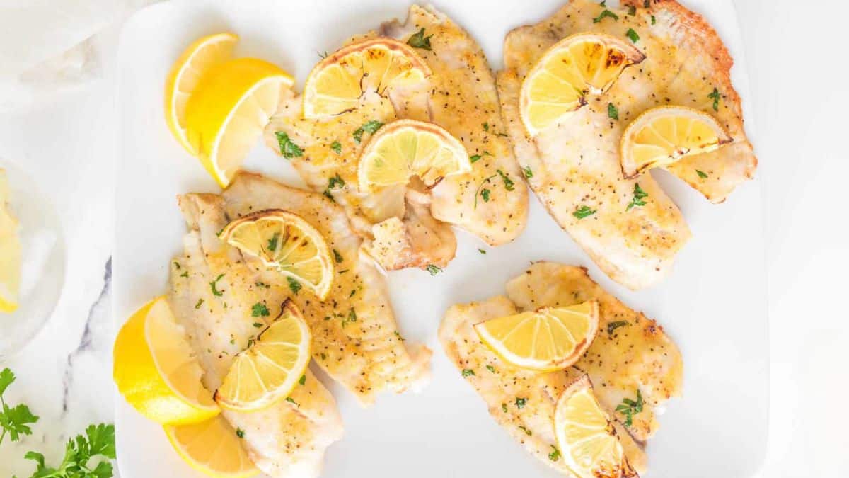 A serving of air fried tilapia topped with lemons. 