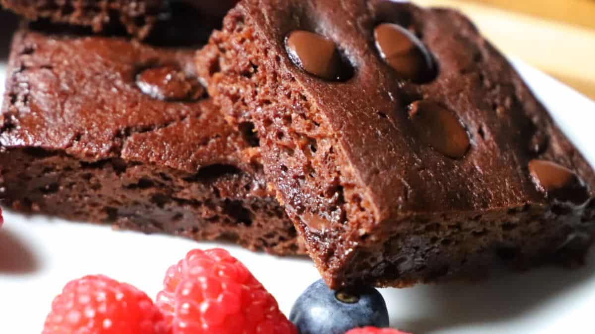 A couple bars of brownies in a plate with some berries on the side