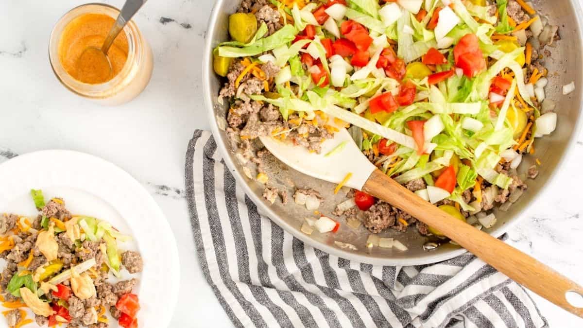 A big bowl of a cooked ground meat, tomatoes, and lots of greens. And a serving of it in a plate on the side.