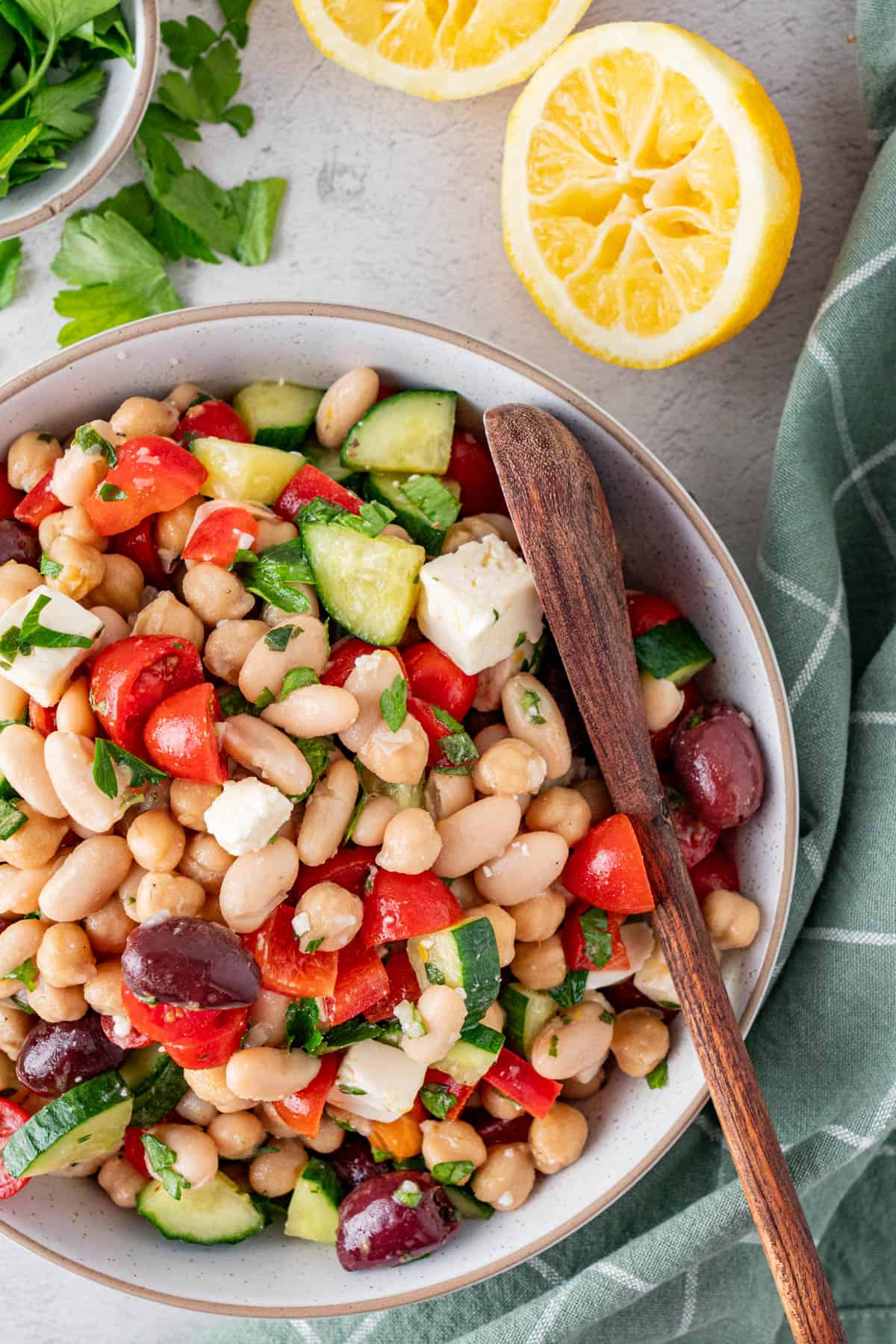 A top shot of Greek Salad in a bowl with a wooden spoon.