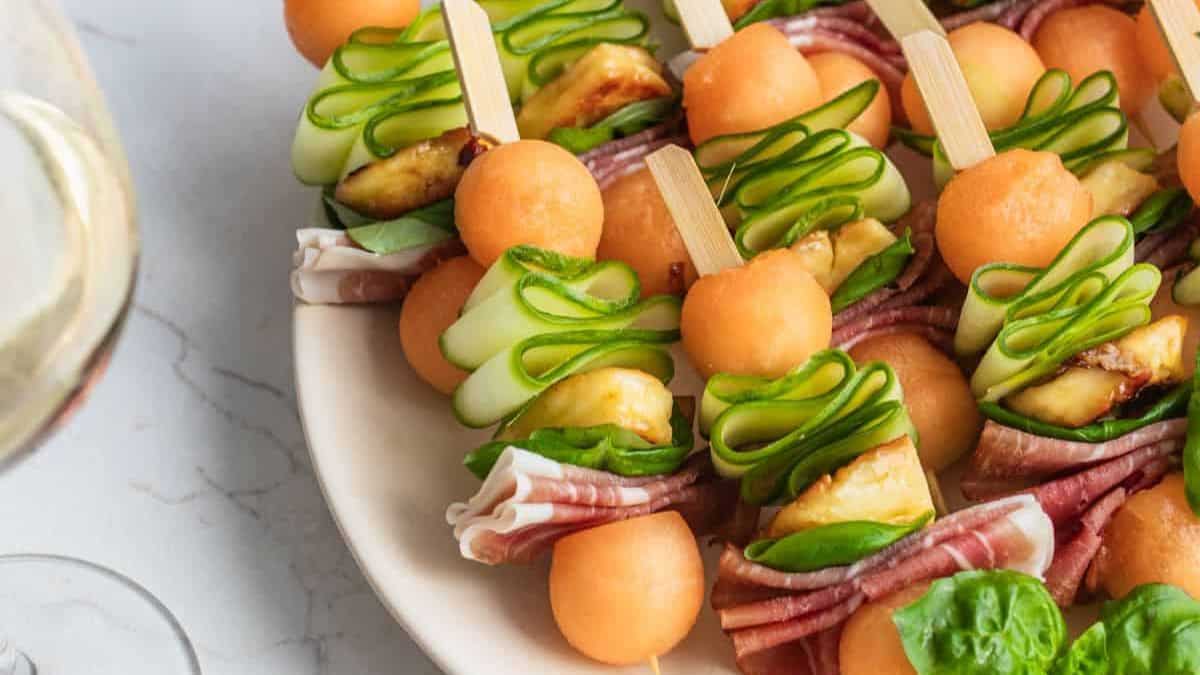A serving of melon and prosciutto skewers with halloumi in a plate.