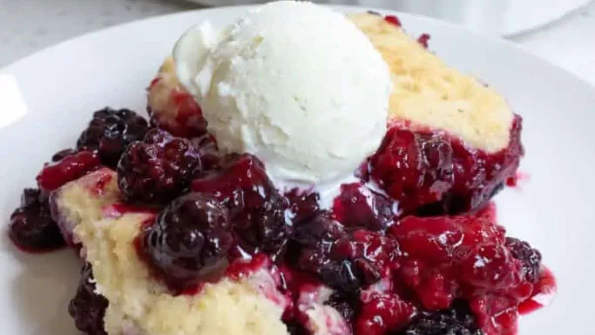 A serving of mixed berry cobbler with vanilla ice cream on top.