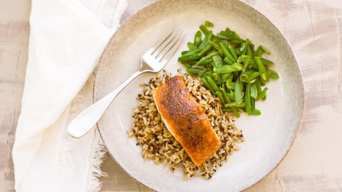 Moroccan Spiced Salmon served in a plate with rice and beans.