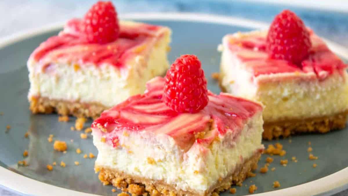 raspberry cheesecake quares with fresh raspberries on top.