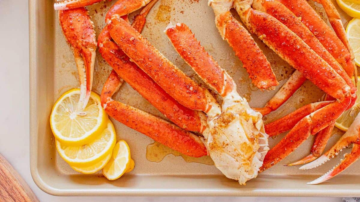 Crab legs in a sheet pan, with lemons on the side.
