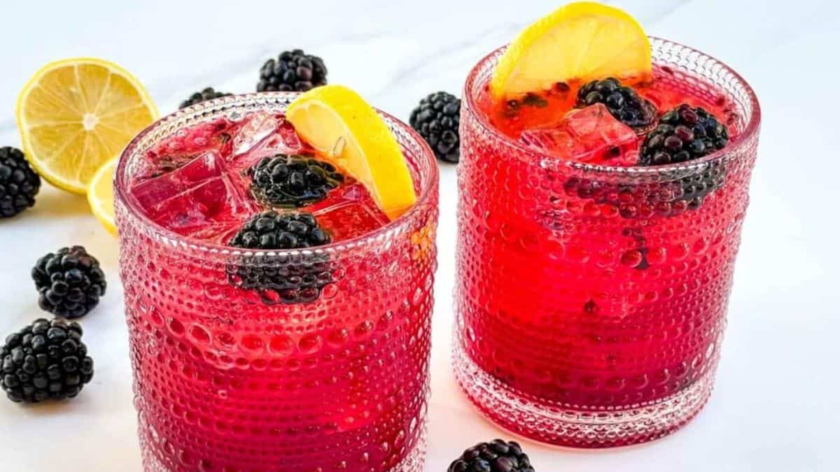 Glasses of sparkling blackberry bramble mocktail with blackberries and slices of lemon.