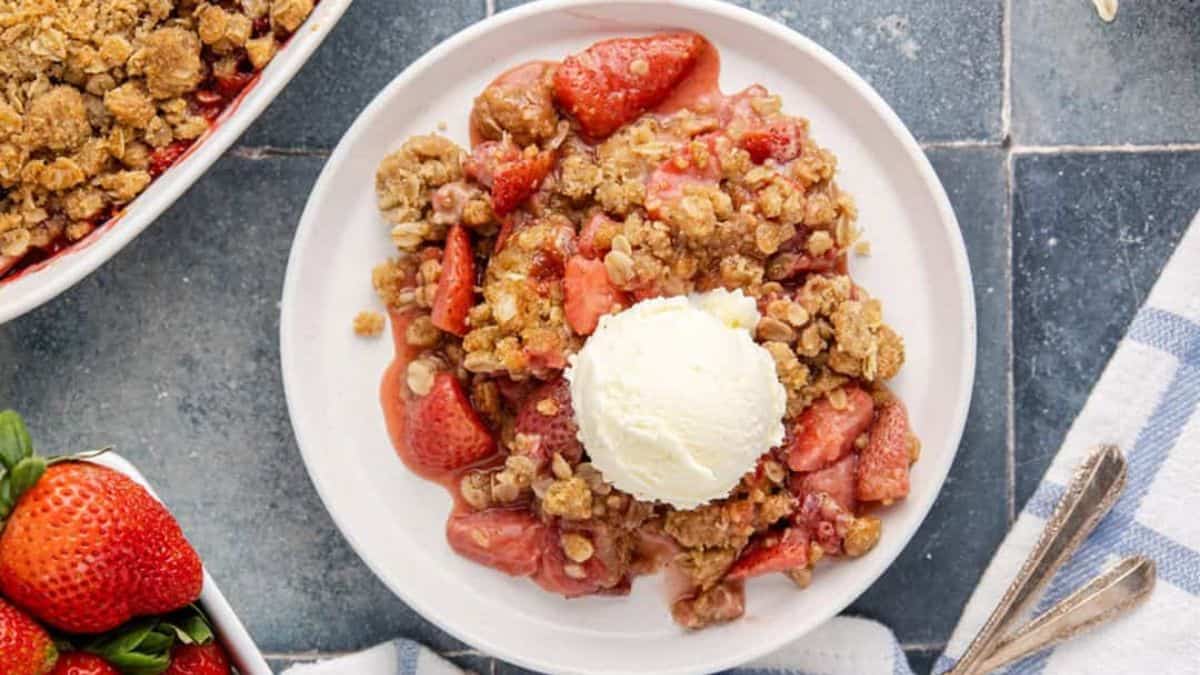 A serving of strawberry crisp with vanilla ice cream on top.