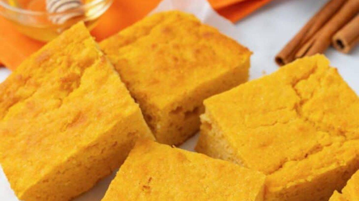 Sweet potato cornbread sliced in squares with honey in a bowl on the side.