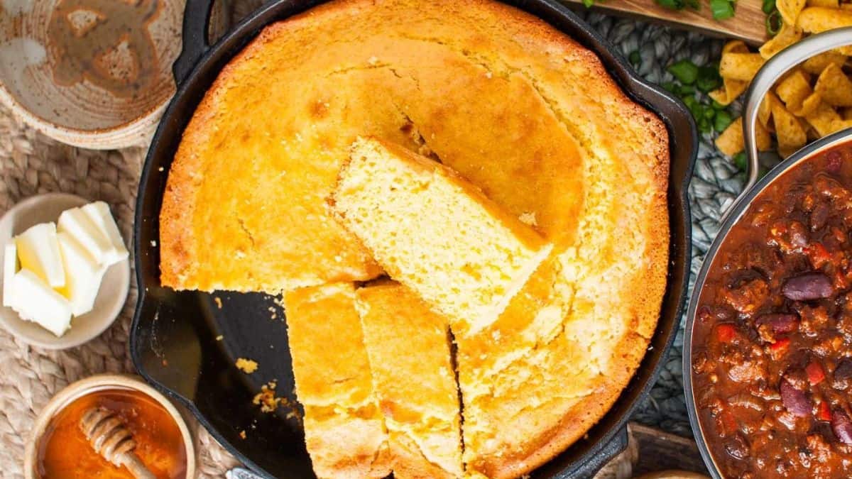 Skillet cornbread with sliced butter, honey, and chilliin on separate bowls.