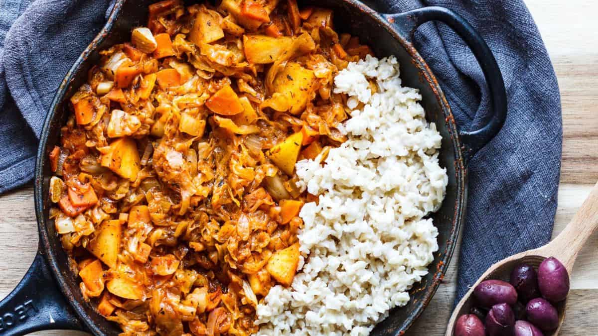 Cabbage Sour Stew in a sauce pan served with some rice on the side. 