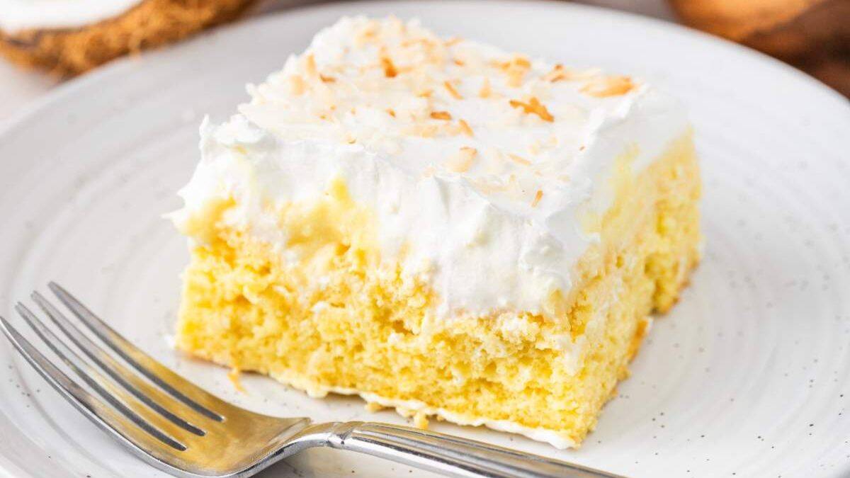 A slice of Coconut Cream Poke Cake served on a plate. 