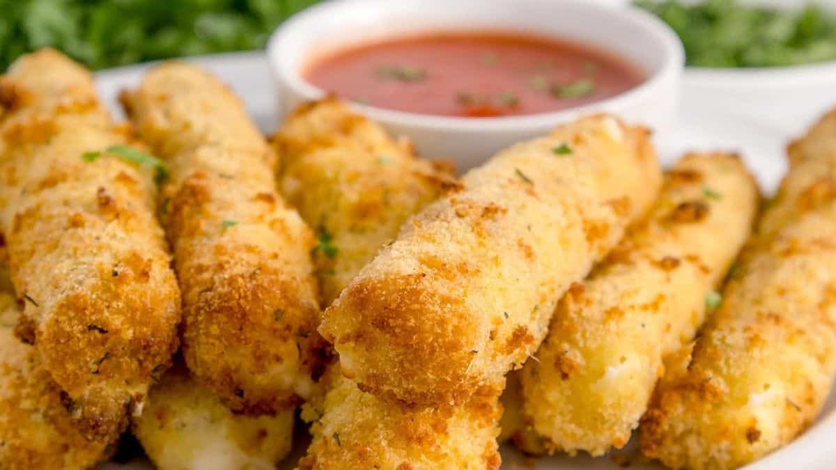 Crispy Air Fryer Mozzarella Sticks served on a plate with a marinara dip.