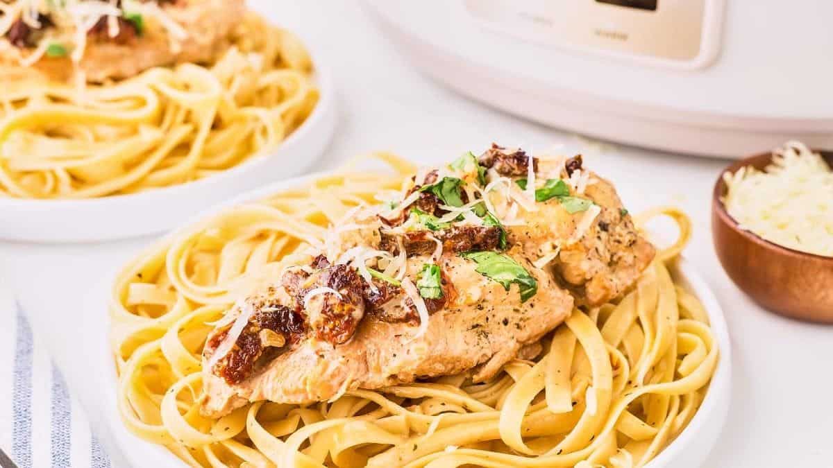 A serving of marry me chicken with pasta on a plate.